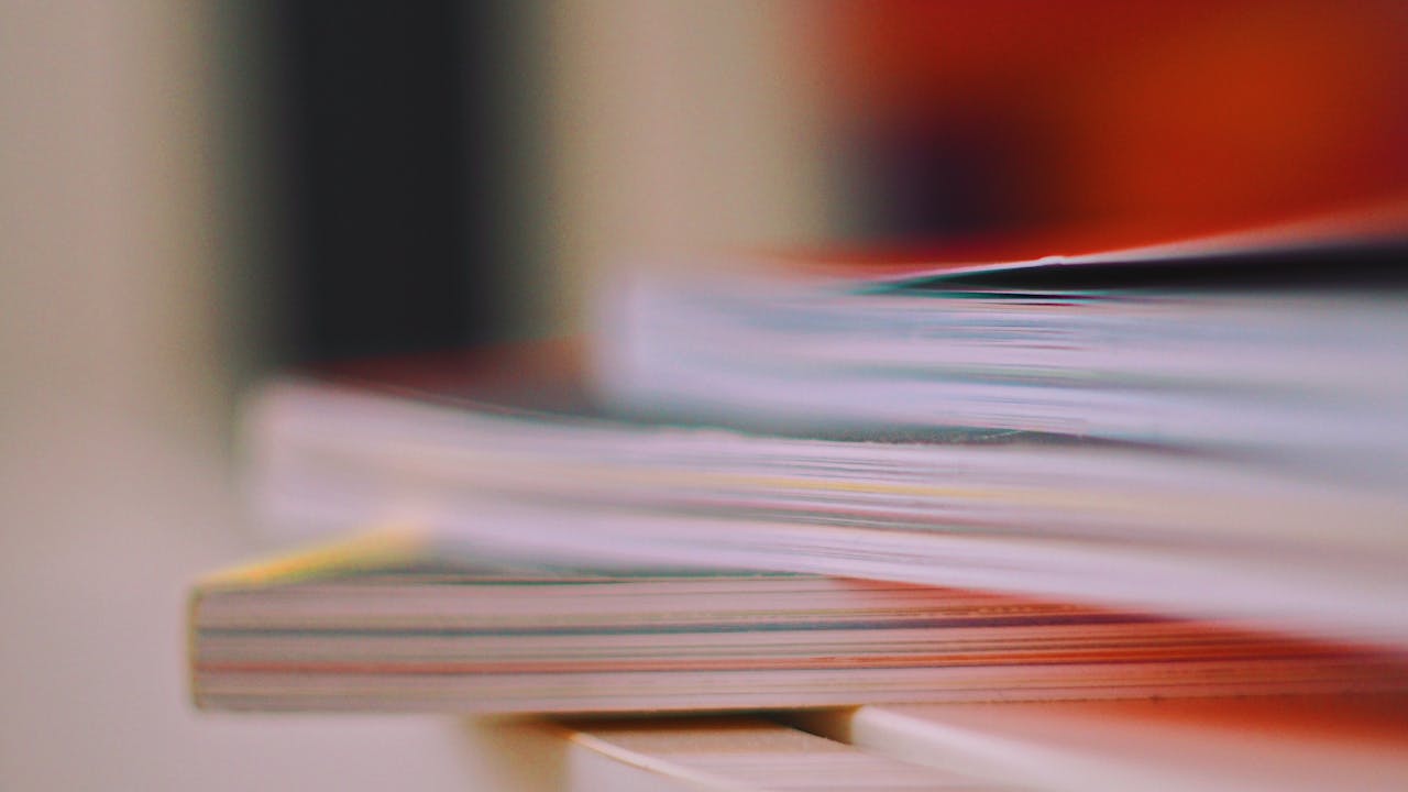Blurred close-up of stacked books and magazines, symbolizing knowledge and education.