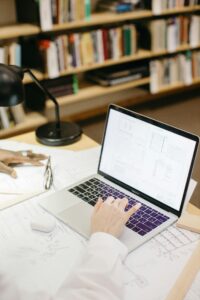 Architect working on laptop with design plans in a modern workspace.